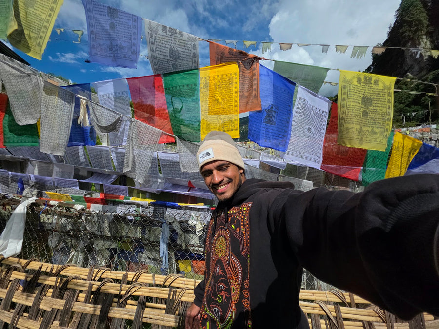 A traveller taking a selfie on a bridge hung with prayer flags
