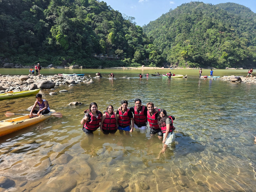 A group in life jackets standing in a clear, shallow river