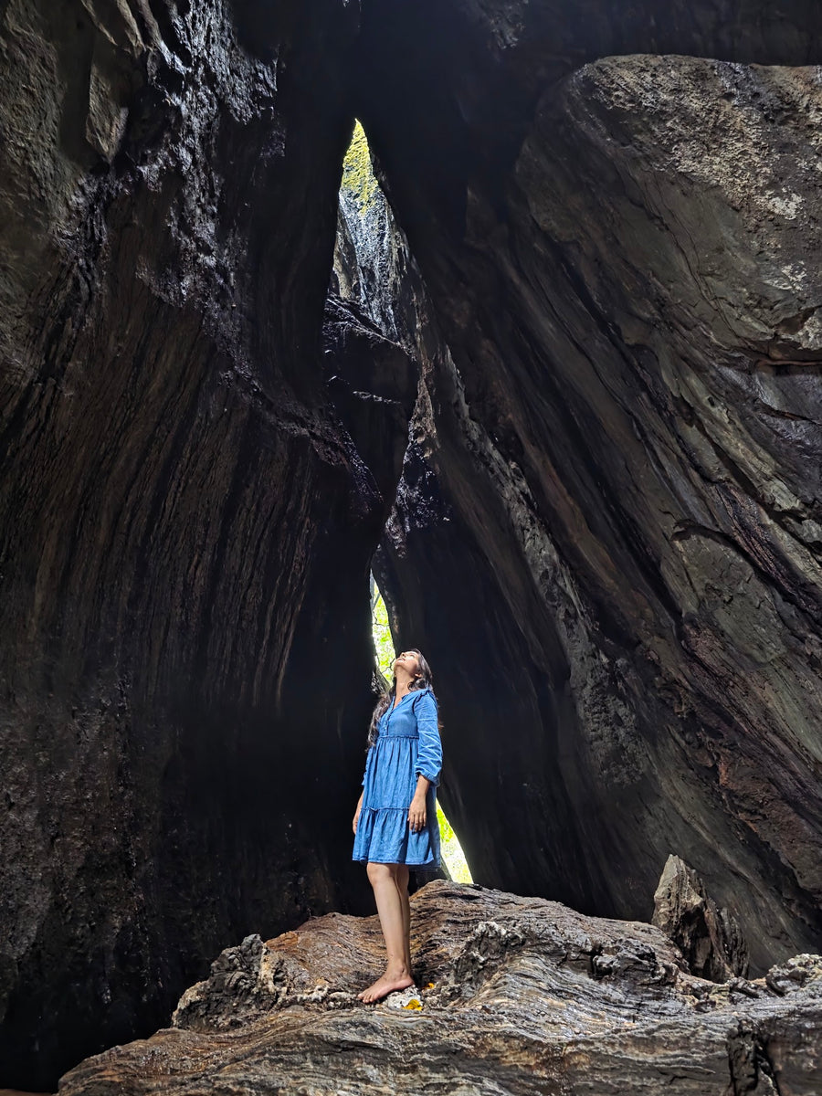 A traveller standing in a shaft of light inside a tall rock cave