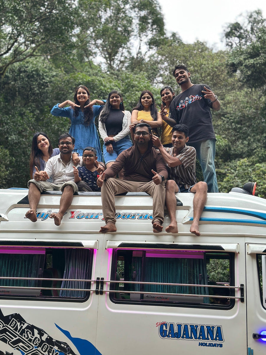 A group sitting on the roof of a tour bus in the forest