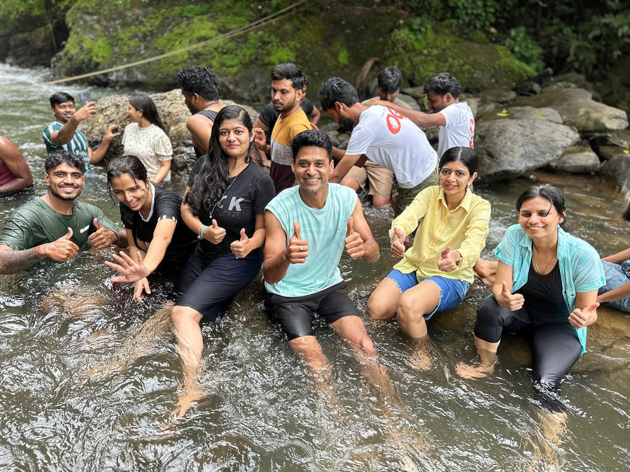 A group sitting in a shallow stream, laughing