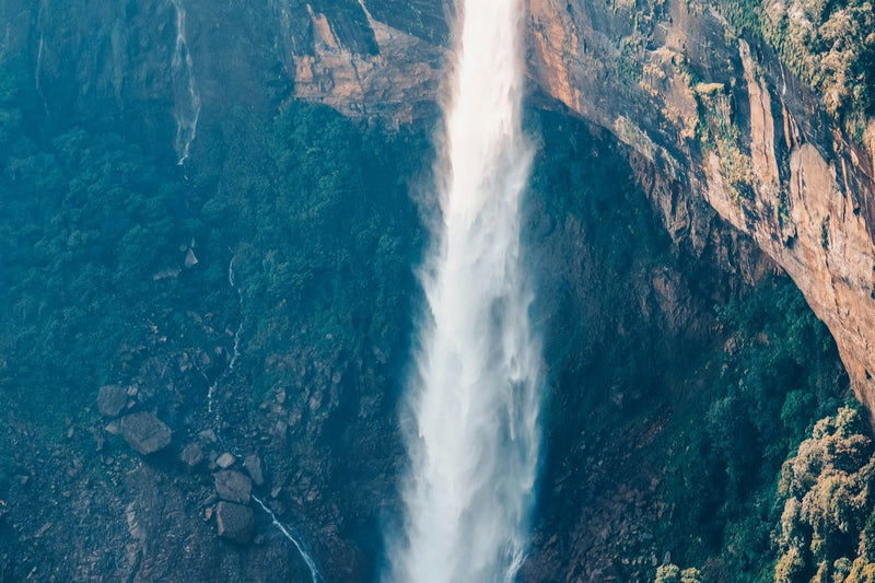 A tall waterfall pouring down a rock gorge at Cherrapunji, seen from above