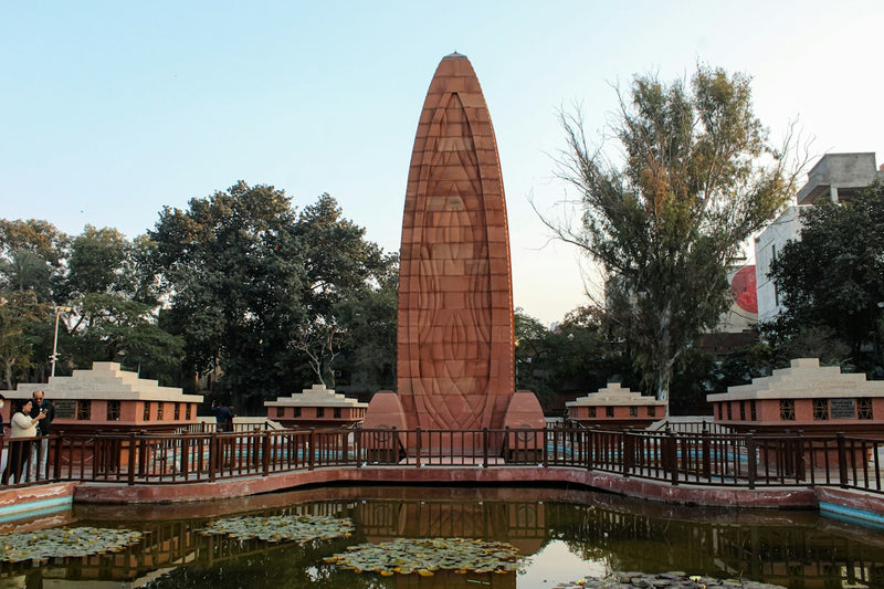 The red stone flame-shaped memorial at Jallianwala Bagh beside a lily pond
