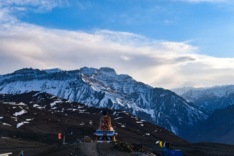 A Buddha statue at Langza village with snow-covered ridges behind