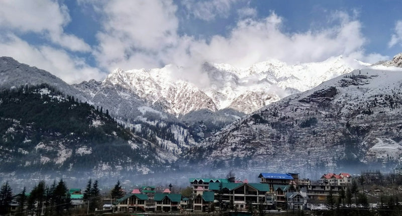 Manali town in the valley with snow-covered mountains rising behind it