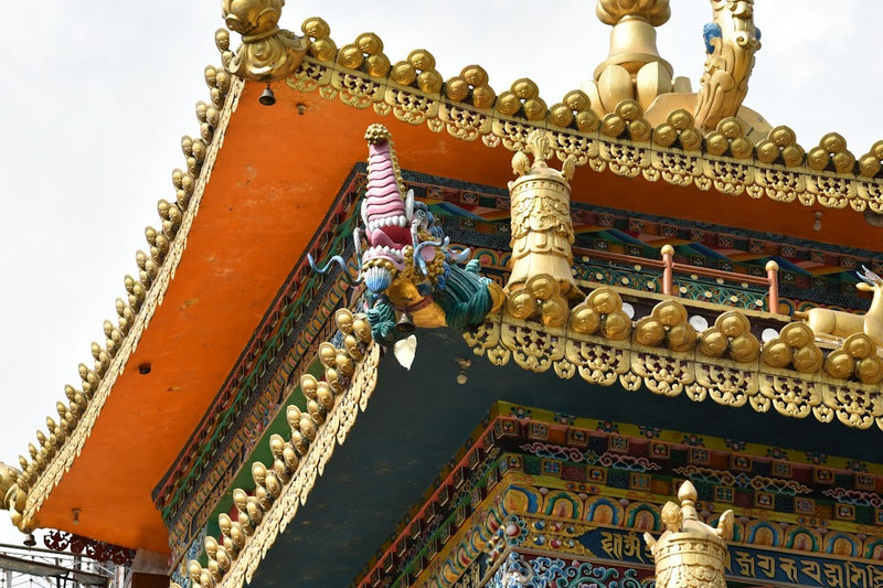 Detail of a Tibetan monastery roof in McLeod Ganj, painted orange and gold with carved figures
