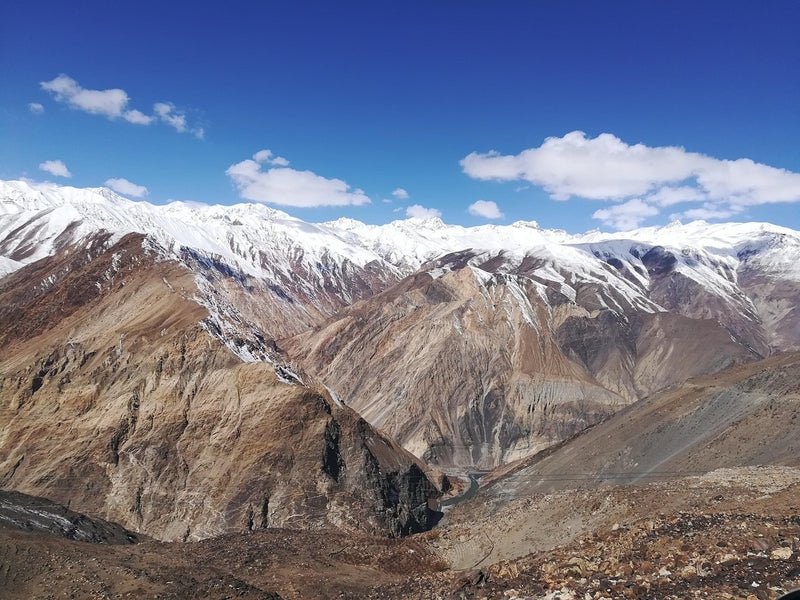 Bare brown mountain slopes under a line of snow peaks near Nako in upper Kinnaur