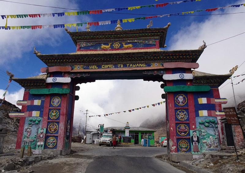 The painted gateway at Sela Pass with prayer flags strung across the road